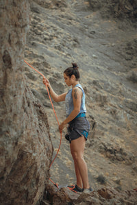 Woman rock climbing in outdoor adventure landscape with safety rope
